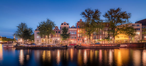 Buildings by river against sky