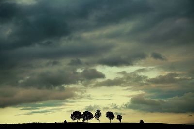 Low angle view of trees against cloudy sky