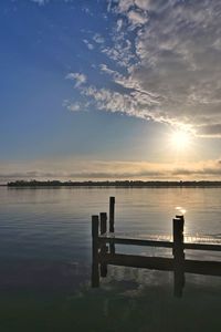 Pier on lake against sky during sunset