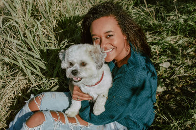 Portrait of young woman with dog sitting on grass