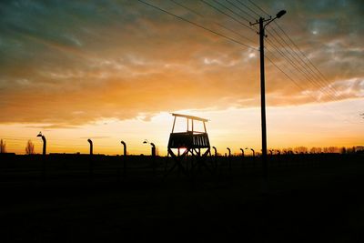 Silhouette electricity pylon against sky during sunset