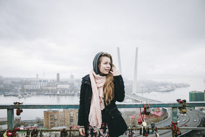 Portrait of young woman against city