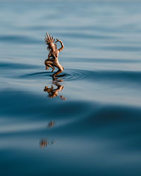 Bronze statuette of hindu goddess dancing on waves of clean blue water in nature