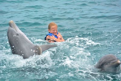 Girl enjoying with dolphins in sea