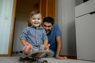 Happy father with baby boy sitting on skateboard