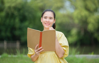 Portrait of a smiling young woman holding book