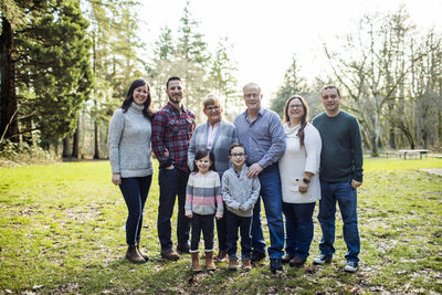 Family of eight posing for photo in park.