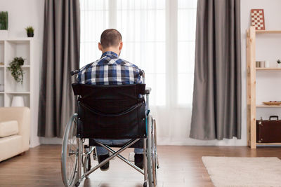 Rear view of man sitting on floor at home