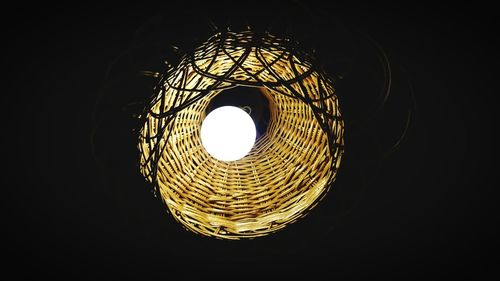 Low angle view of illuminated lighting equipment against black background