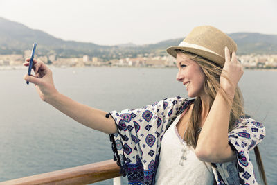 Smiling woman on cruise liner taking selfie with smartphone