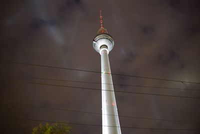 Low angle view of communications tower against cloudy sky