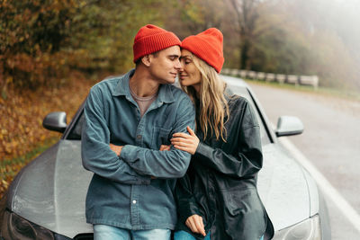 Boyfriend and girlfriend is embarrassing on the road near by car.