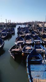 Boats moored at harbor against clear sky