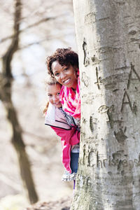 Mother and girl behind tree