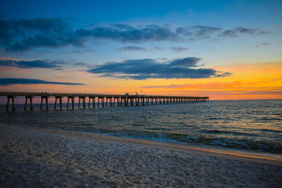 Pier over sea against sky during sunset