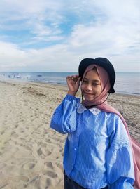 Woman wearing sunglasses on beach against sky