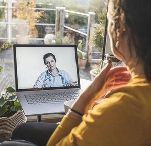 Woman using mobile phone while sitting in laptop