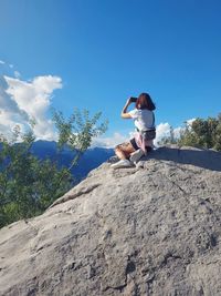 Woman sitting on rock taking pictures