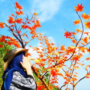 Low angle view of woman against tree and sky during autumn 