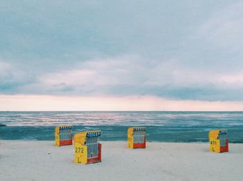 Deck chairs on beach against sky