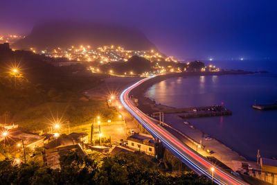 High angle view of light trails on street by sea at night