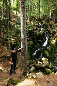 Man standing by waterfall in forest