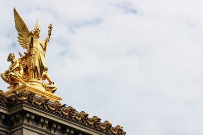 Low angle view of angel statue against cloudy sky