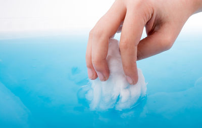 Cropped hand of person soaking cotton in blue water