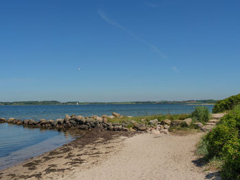 Scenic view of beach against clear blue sky