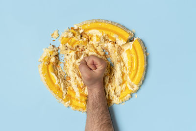 Man's fist smashing a cake. concept for dieting, an orange whipped cream cake destroyed by a man.