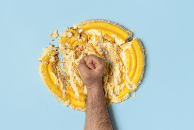 Close-up of hand holding yellow against blue background