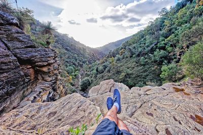 Low section of man standing on rocky mountain