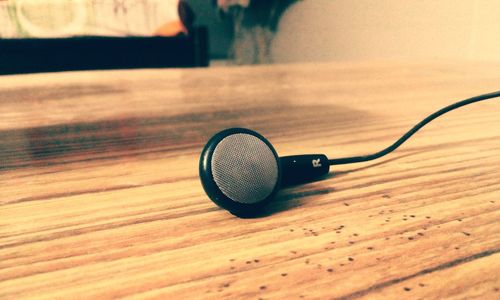 Close-up of in-ear headphones on wooden table