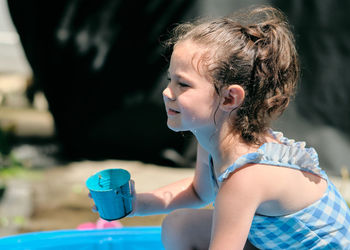 Siblings playing near a water basin in the back yard