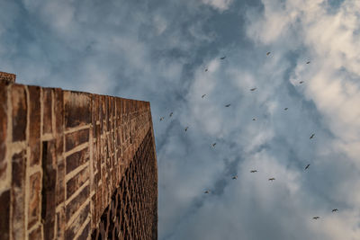 Low angle view of wall under cloudy sky