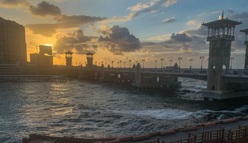 Scenic view of sea by buildings against sky during sunset