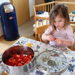 High angle view of cute girl cleaning strawberry on table at home