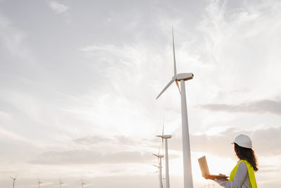 Wind turbines at sunset with engineer holding laptop