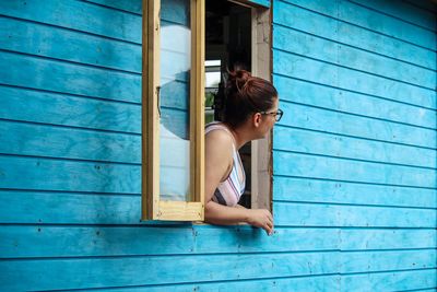 Woman sitting against blue window