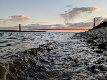 Bridge over sea against sky during sunset