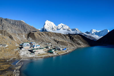 Scenic view of lake and mountains against clear blue sky