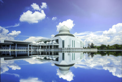 Reflection of building in lake against cloudy sky