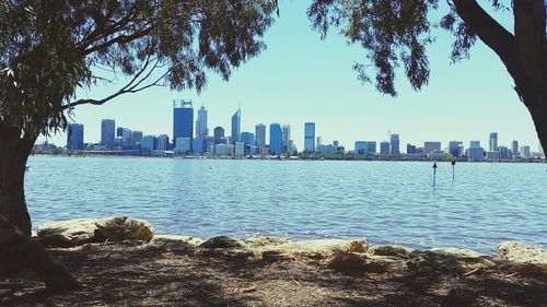 City skyline by sea against clear sky