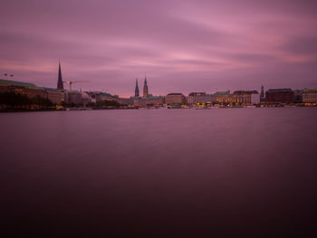 City at waterfront against cloudy sky