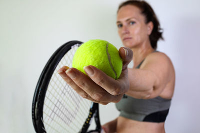Portrait of woman holding ball over white background