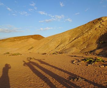 Shadow of person on sand dune in desert against sky