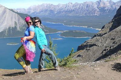 Portrait of smiling young woman standing on mountain against sky