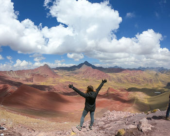 Rear view of man jumping on mountain against sky