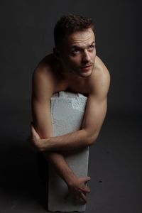 Portrait of young man looking away over black background