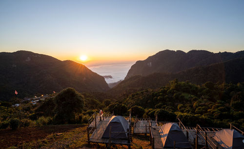 Tourist tent with mountains and light of sunrise, blue sky and morning mist in thailand.